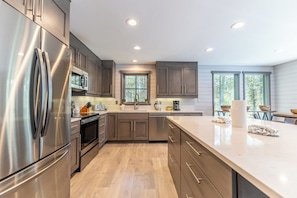 A modern kitchen with stainless steel appliances, wooden cabinets, and a large island. - 45fmnl-5 (Keystone)