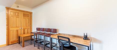 A room with a wooden desk, four chairs, a bench, and a wooden wardrobe.