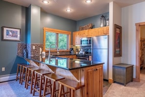 A kitchen with a central island, wooden bar stools, a refrigerator, and a microwave. - Es8568-2 (Keystone)