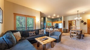 Una sala de estar con sofá, sillón y mesa de centro, una cocina con armarios de madera, y un comedor con mesa y sillas de madera.