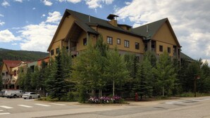 A large, multi-story building with a prominent gabled roof, surrounded by trees and a crosswalk. - Expedition Station #8576 (Keystone)