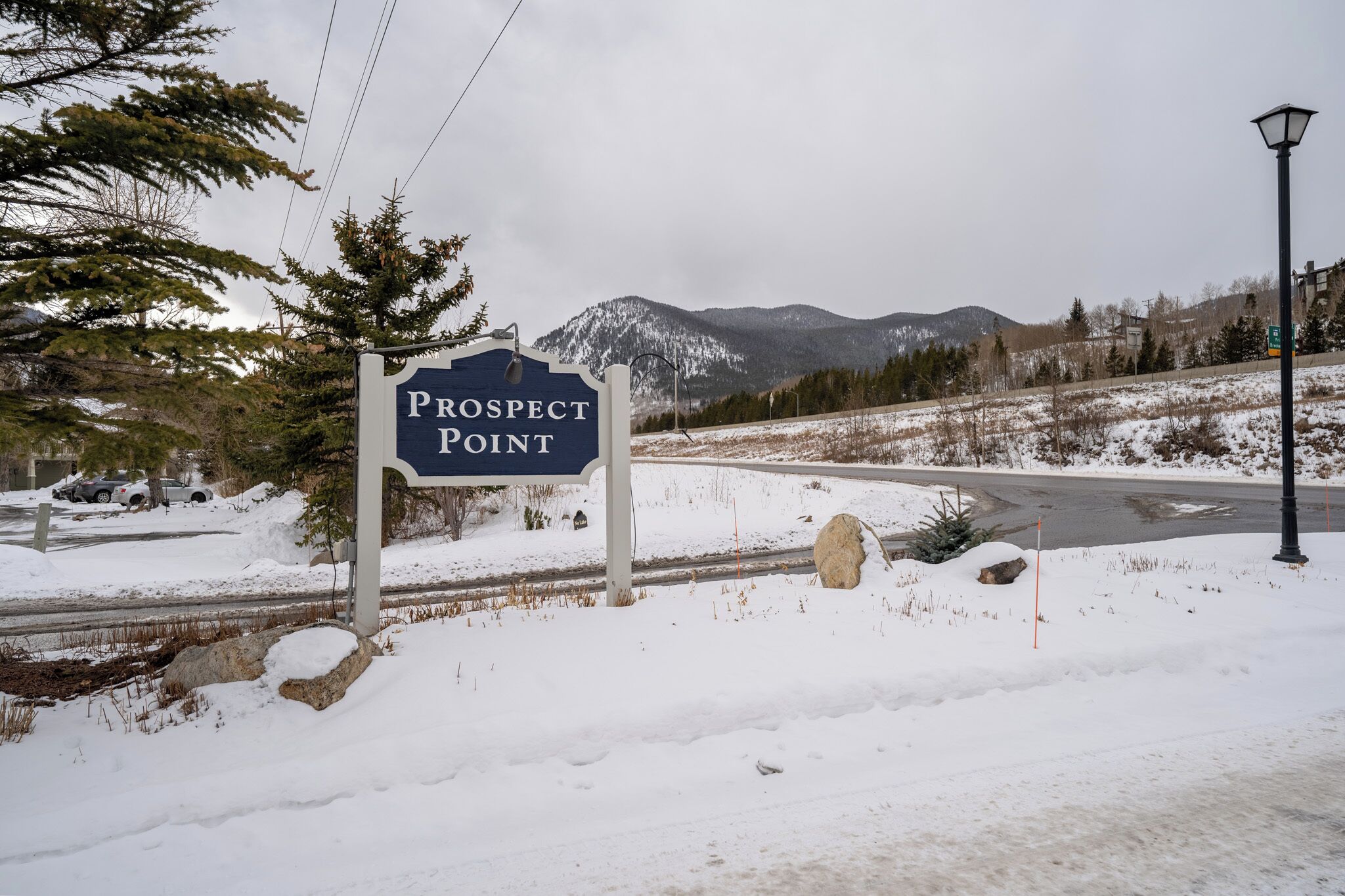 Un senyal amb la lectura “Prospect Point”, fons de muntanyes, carretera i paisatge cobert de neu.