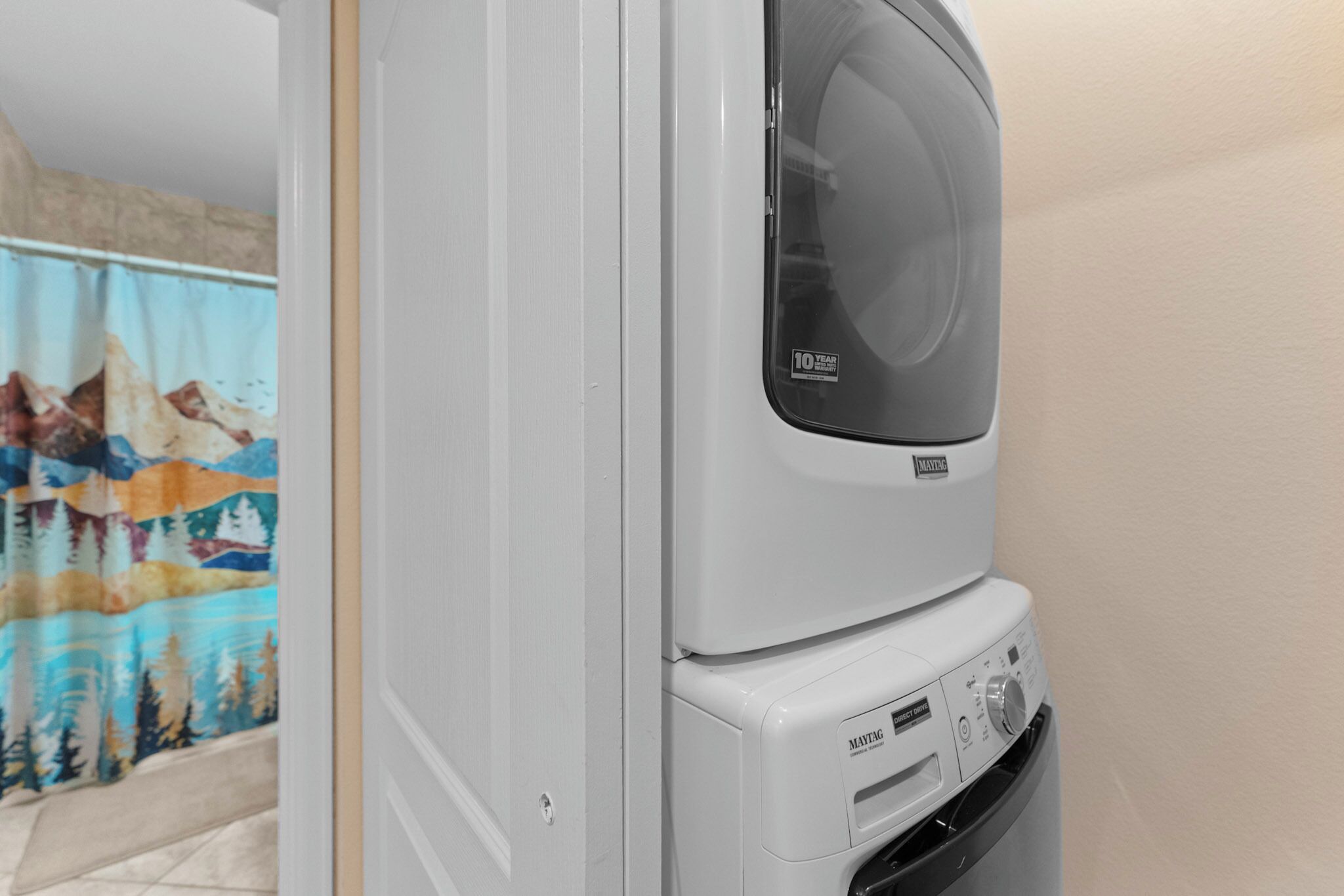 Vue de face d’un appareil combiné lave-linge et sèche-linge, avec le panneau de commande visible et un autocollant indiquant une garantie de 10 ans.