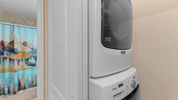 Vue de face d’un appareil combiné lave-linge et sèche-linge, avec le panneau de commande visible et un autocollant indiquant une garantie de 10 ans.