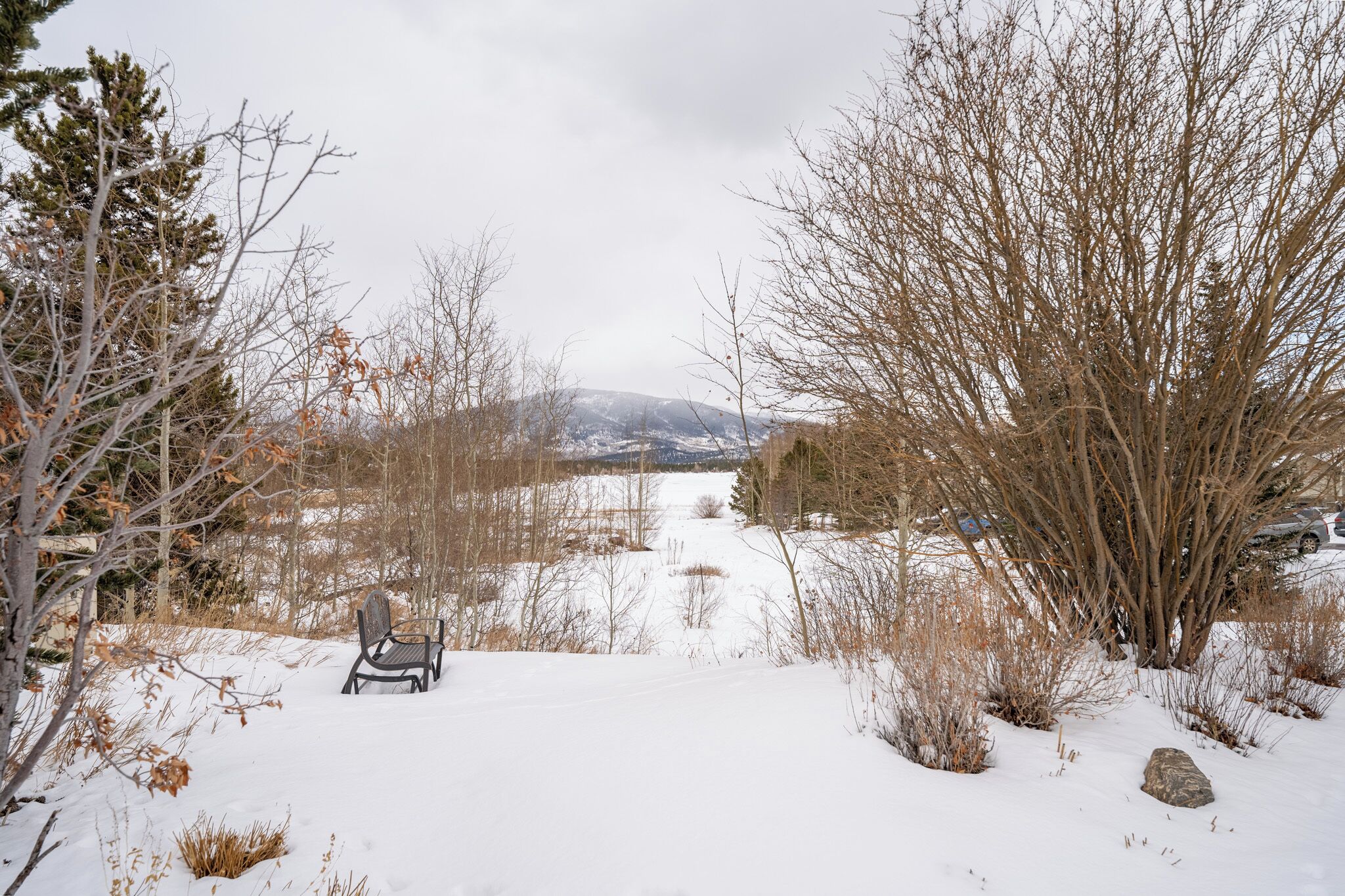 Schneebedeckte Landschaft mit einem Stuhl im Vordergrund und Blick auf Berge in der Ferne.