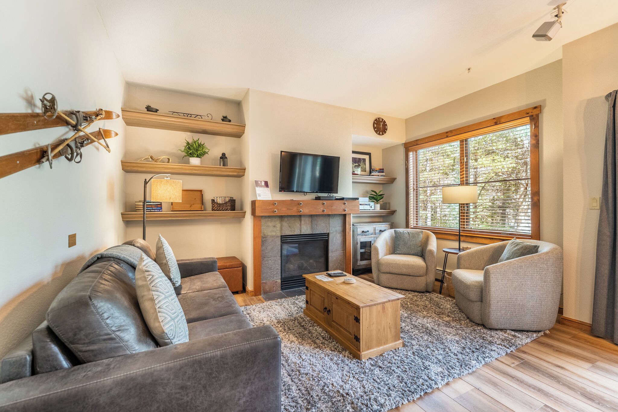 A living room with a fireplace, a television, and a large window.