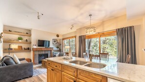 Une cuisine moderne avec des meubles en bois, un grand îlot central doté d’un évier et un coin repas avec une table et des chaises.