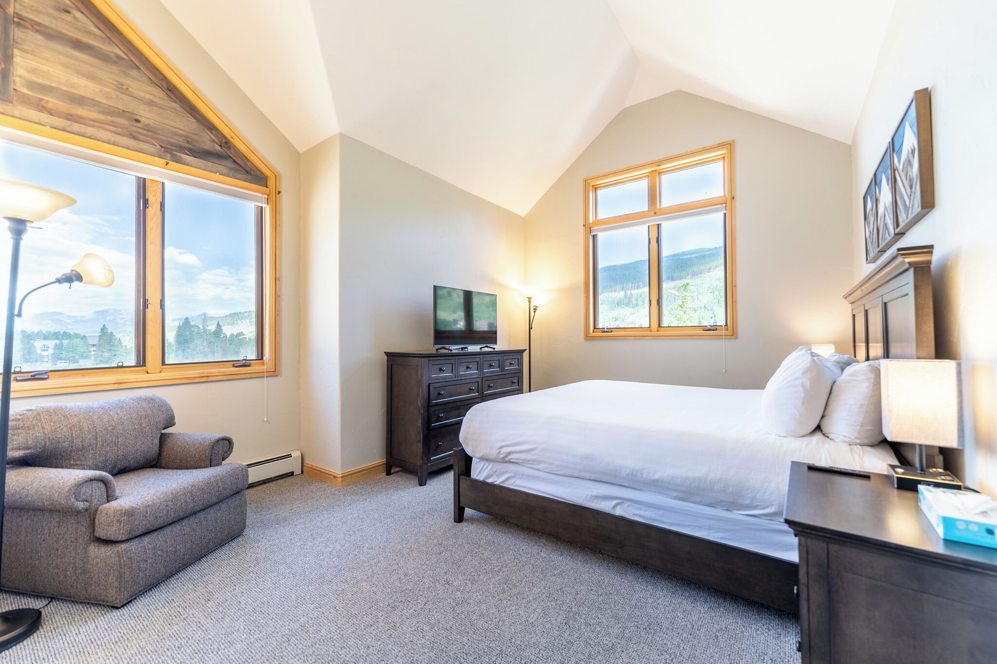 A bedroom with a large bed, a dresser, a TV, and a chair.