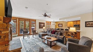 A spacious living room with a fireplace, a large sofa, a coffee table, and a kitchen area in the background. - T30734 (Keystone)