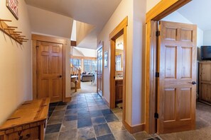 A hallway with wooden doors, a bench, and a dining table.