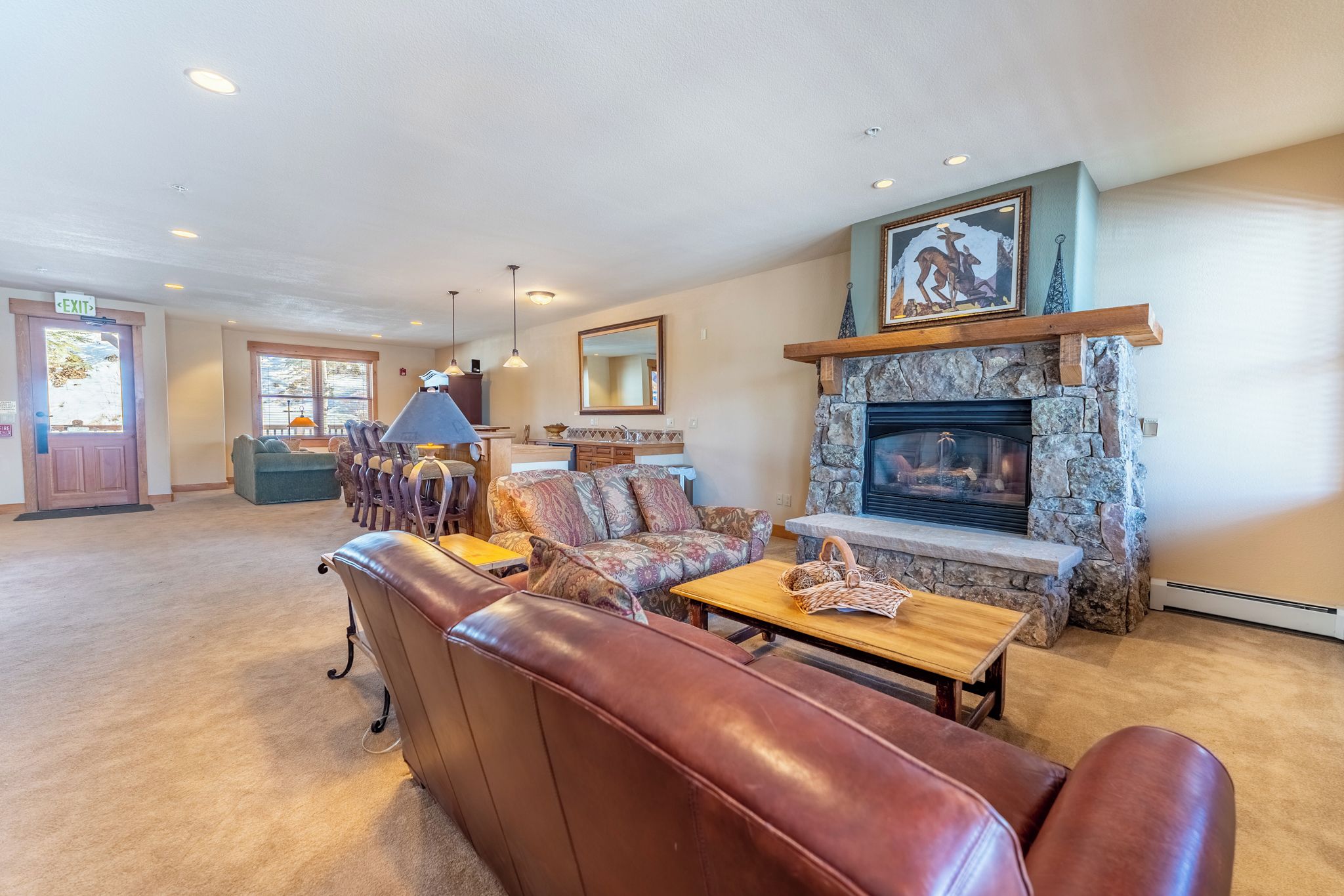 A spacious lobby with leather seating, a stone fireplace, and a large mirror.