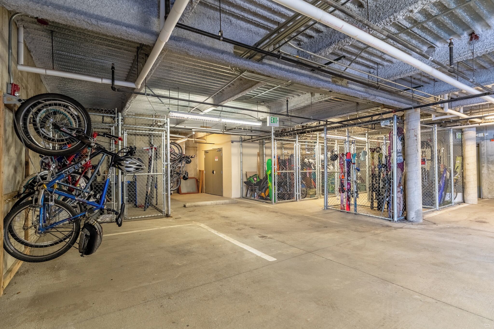 Zona de almacenamiento de bicicletas techada con estantes metálicos y suelo de concreto.