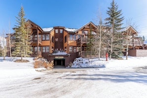 A large, multi-story lodge with a prominent entrance and a snow-covered driveway. - Er9576k2 (Keystone)