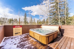 A wooden deck with a hot tub and a sign listing spa rules. - Er9576k2 (Keystone)