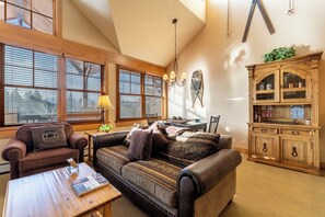 A cozy living room with a brown leather sofa, a wooden coffee table, and a wooden cabinet with glass doors.