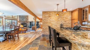 Una cocina amplia con una isla grande, pared de piedra y vigas de madera.