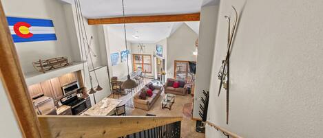 A spacious living area with a high ceiling, wooden beams, a kitchen with modern appliances, and a dining area with a large table and chairs.