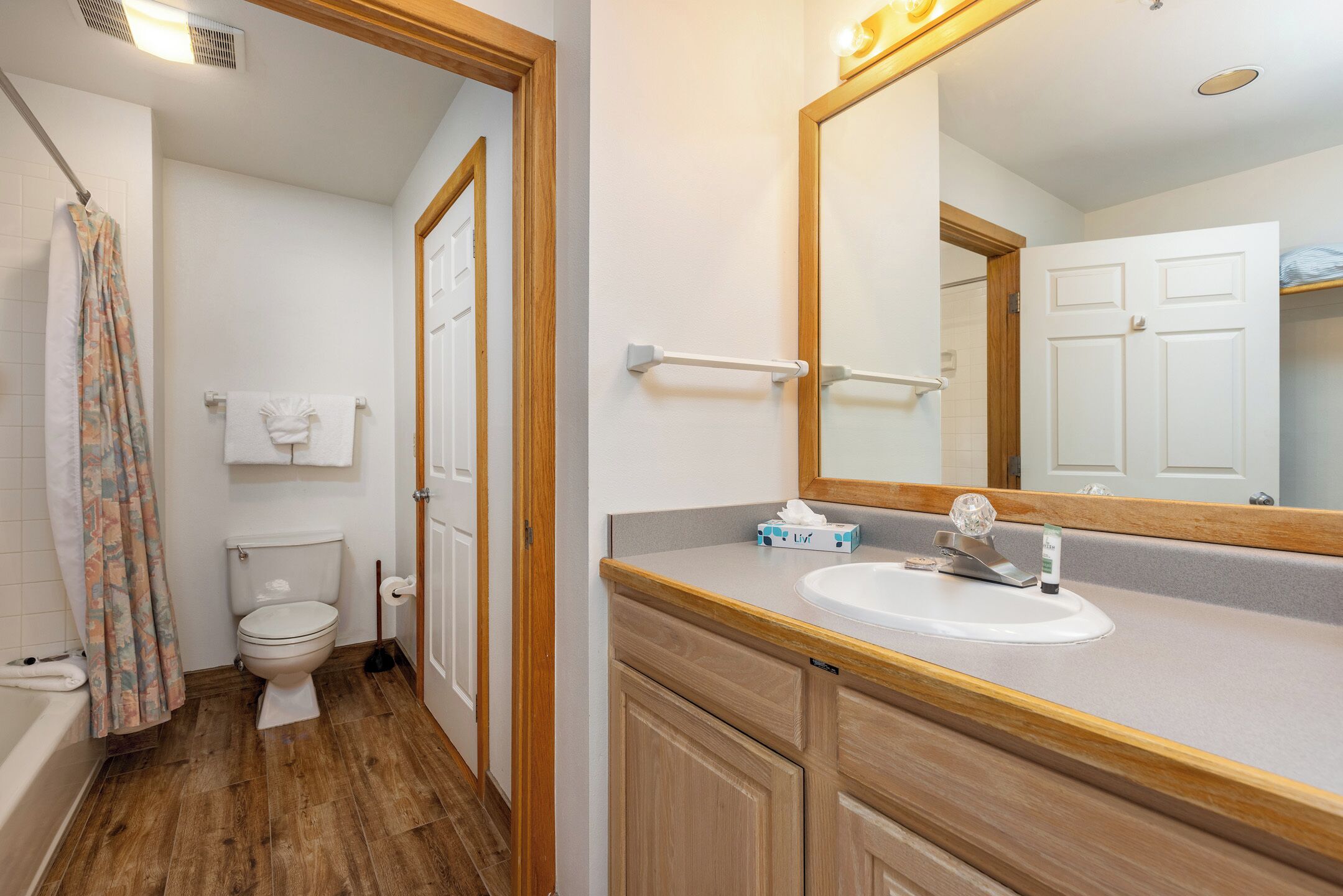 Un baño con inodoro, lavabo, espejo y cortina de ducha.