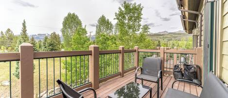 A wooden deck with outdoor seating and a view of a mountainous landscape.