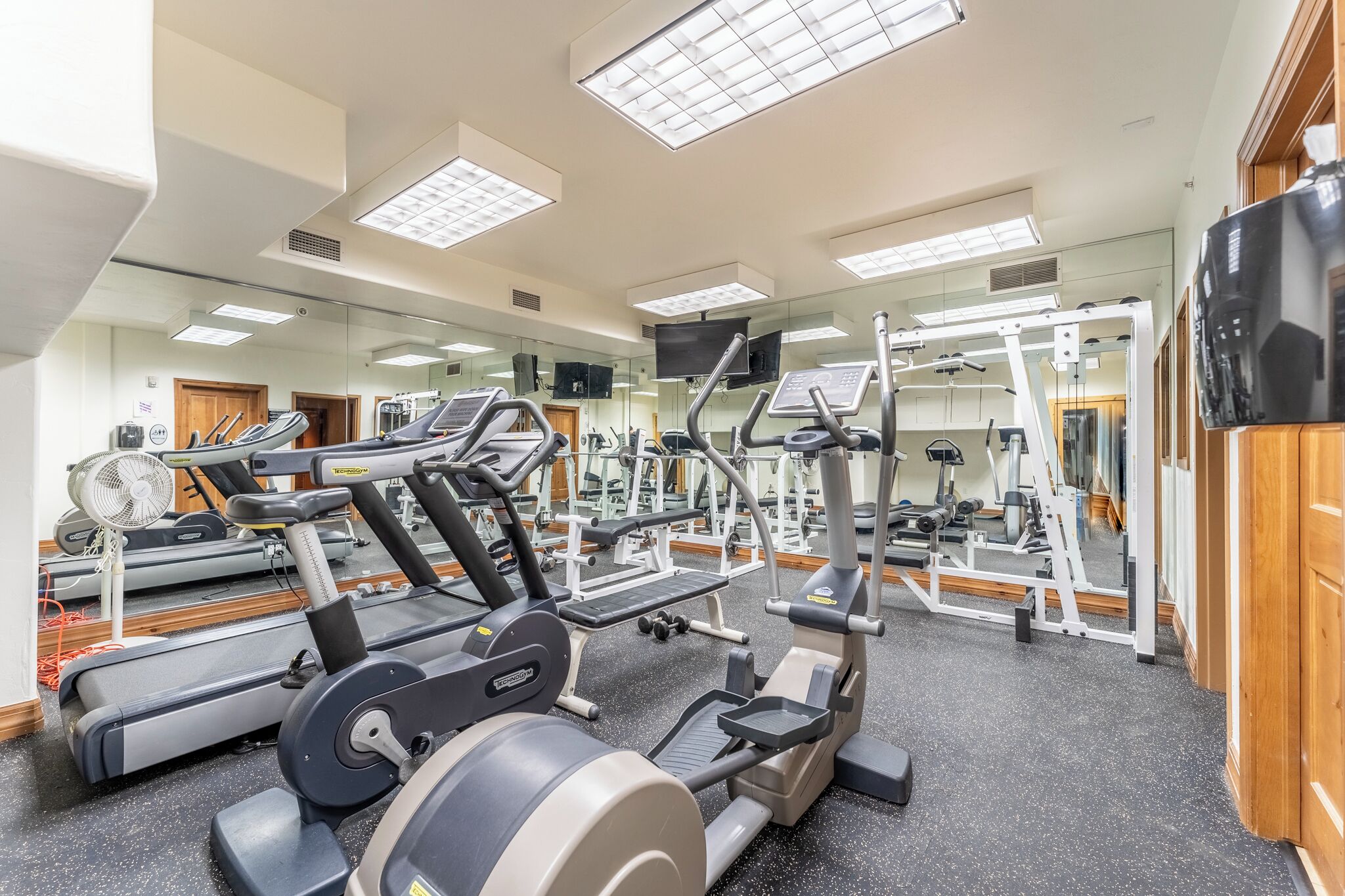 Una palestra con diverse attrezzature per esercizi, specchi e un televisore.