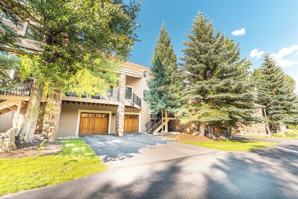 A two-story building with a stone facade, a covered driveway, and a well-maintained lawn.