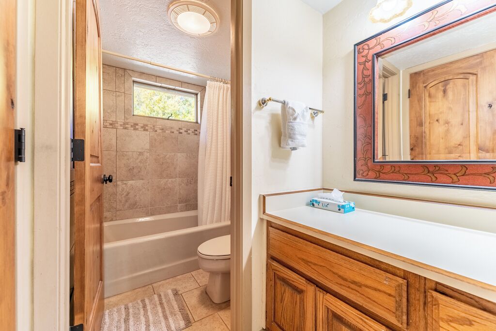 A bathroom with a bathtub, toilet, and a vanity with a mirror.