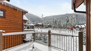 En træhytte med balkon med udsigt over et sneklædt landskab og et bjerg i baggrunden.