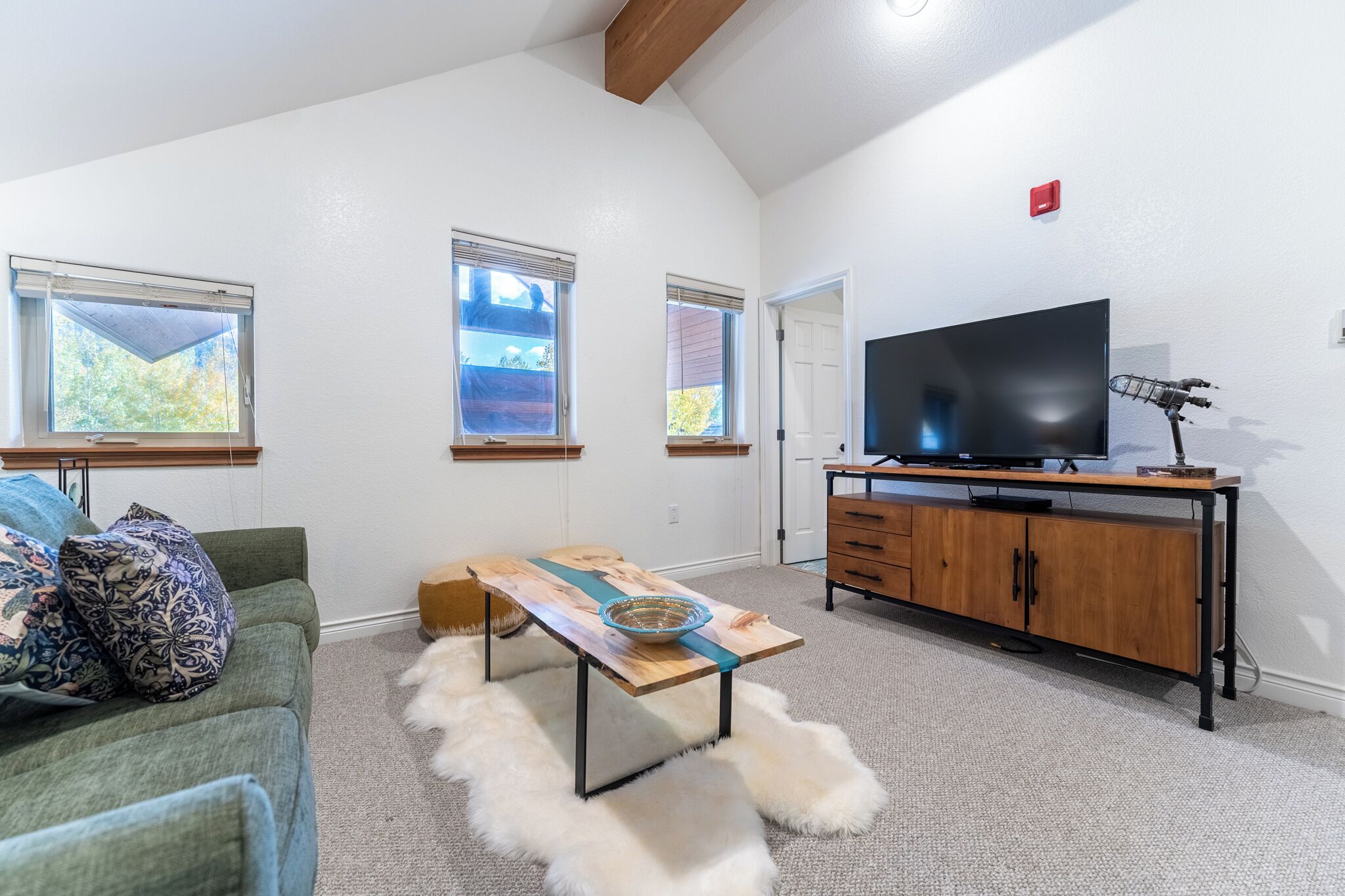 Una sala de estar con sofá, mesa de centro, televisor y mueble de madera.