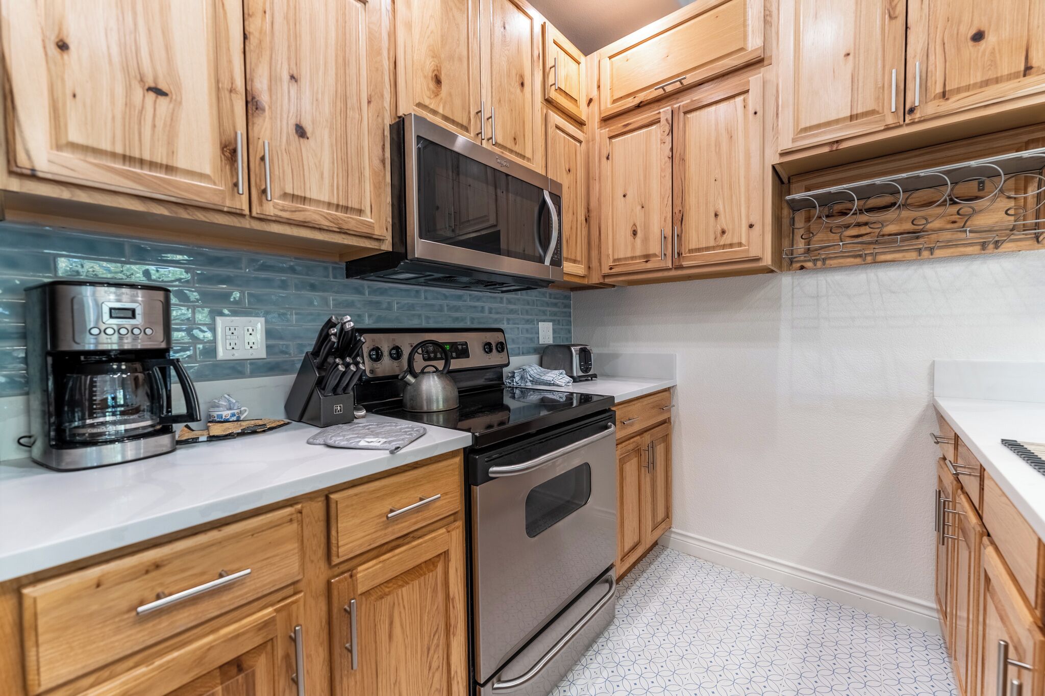 A kitchen with wooden cabinets, a stainless steel microwave, a coffee maker, and a stove.