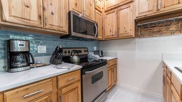 A kitchen with wooden cabinets, a stainless steel microwave, a coffee maker, and a stove.