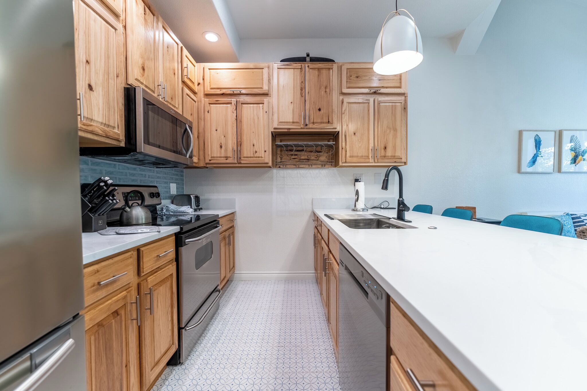 A modern kitchen with wooden cabinets, a stainless steel refrigerator, a microwave, and a sink.