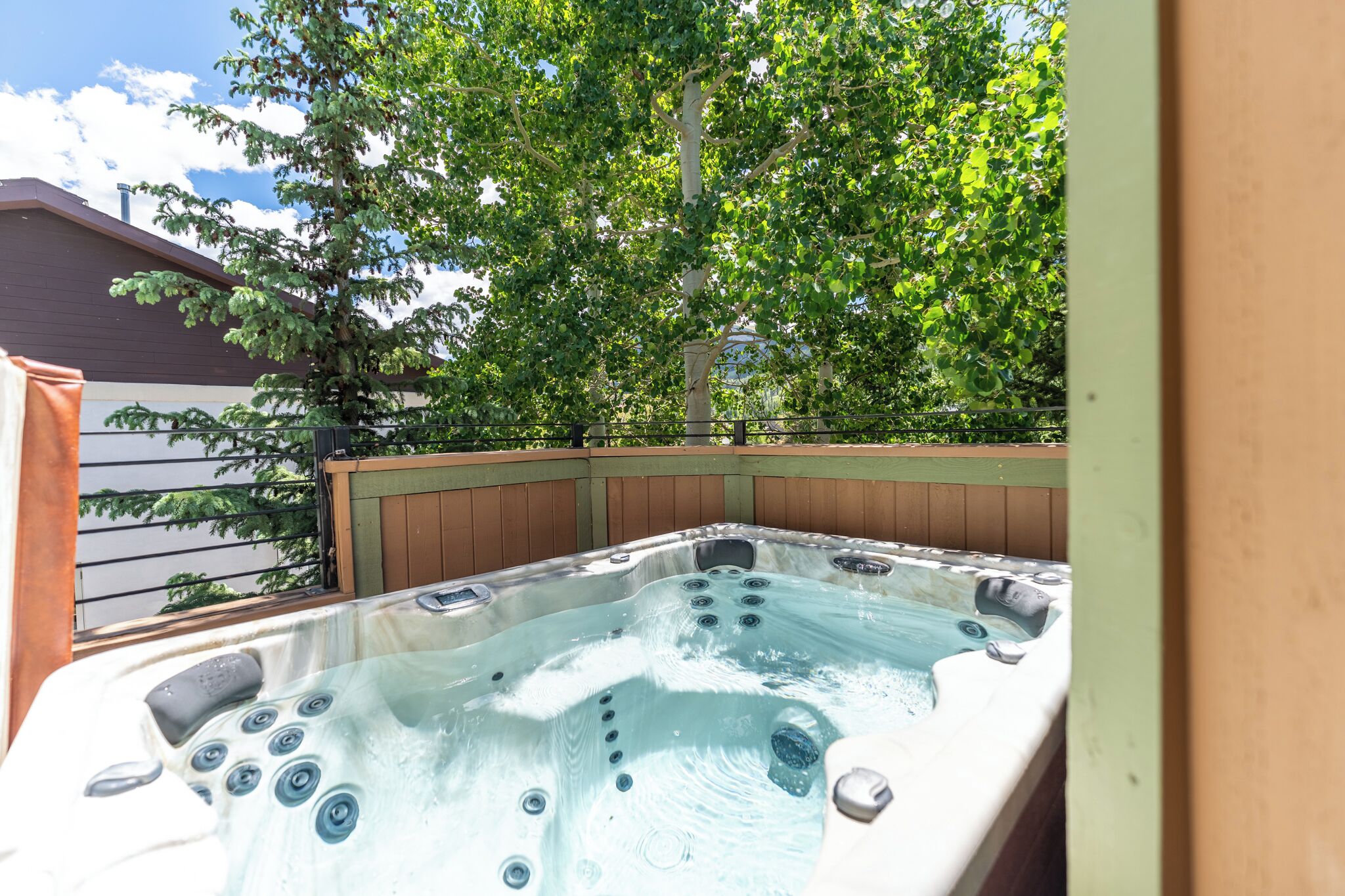 A hot tub with multiple jets, surrounded by a wooden deck and a tree.
