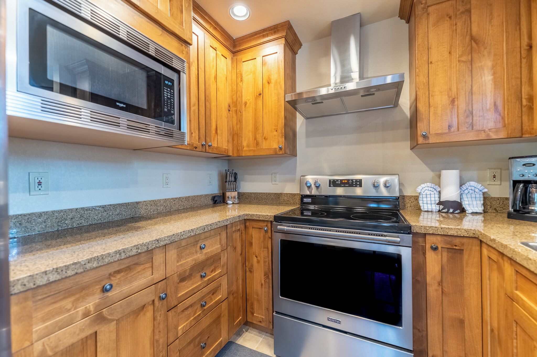 A kitchen with wooden cabinets, a microwave, a stove, and a coffee maker.