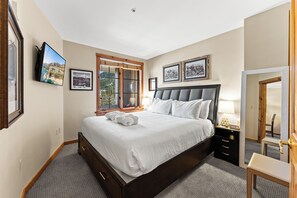 A neatly arranged bedroom with a large bed, a bedside table with a lamp, a chair, and a mirror.