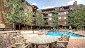 A pool area with wooden deck chairs and a pool. - Dakota Lodge #8492 (Keystone)