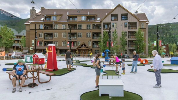 A hotel with a large building, outdoor play area, and a red telephone booth. - Dakota Lodge #8492 (Keystone)