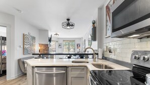 A modern kitchen with stainless steel appliances, a large island with a sink, and a black stove. - Dakota Lodge #8492 (Keystone)