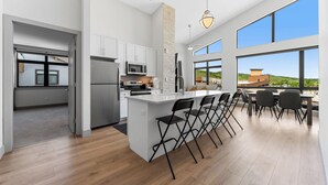 A modern kitchen with a central island, white cabinetry, and large windows offering a view of the outdoors. - Skywalk Flats #305e : 2 (Silverthorne)