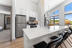 A modern kitchen with white cabinets, stainless steel appliances, and a large island with bar seating.