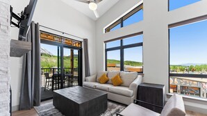 A modern living room with a sofa, coffee table, and a view of a cityscape through large windows. - Skywalk Flats #305e : 2 (Silverthorne)