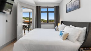 A modern hotel room with a large bed, a ceiling fan, a flat-screen TV, and a window with a view of the countryside. - Skywalk Flats #305e : 2 (Silverthorne)