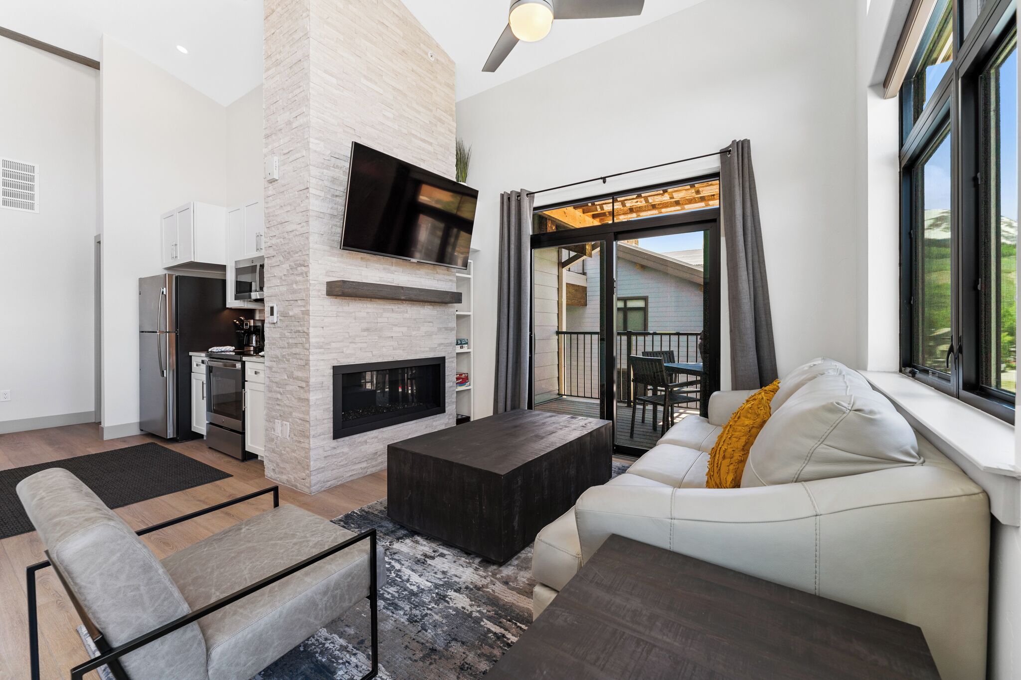 Een moderne woonkamer met een open haard, een flatscreen televisie, een bank en een eethoek met een tafel en stoelen.