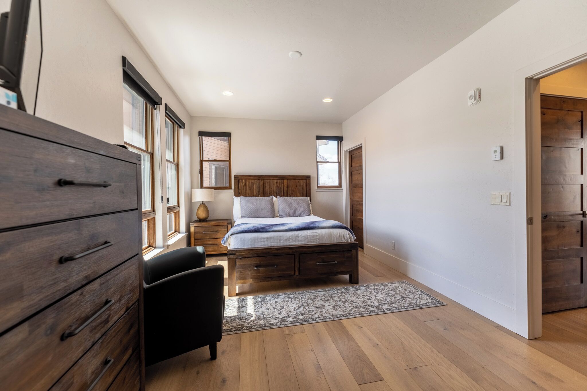 A bedroom with a wooden bed, a dresser, a chair, and a rug.