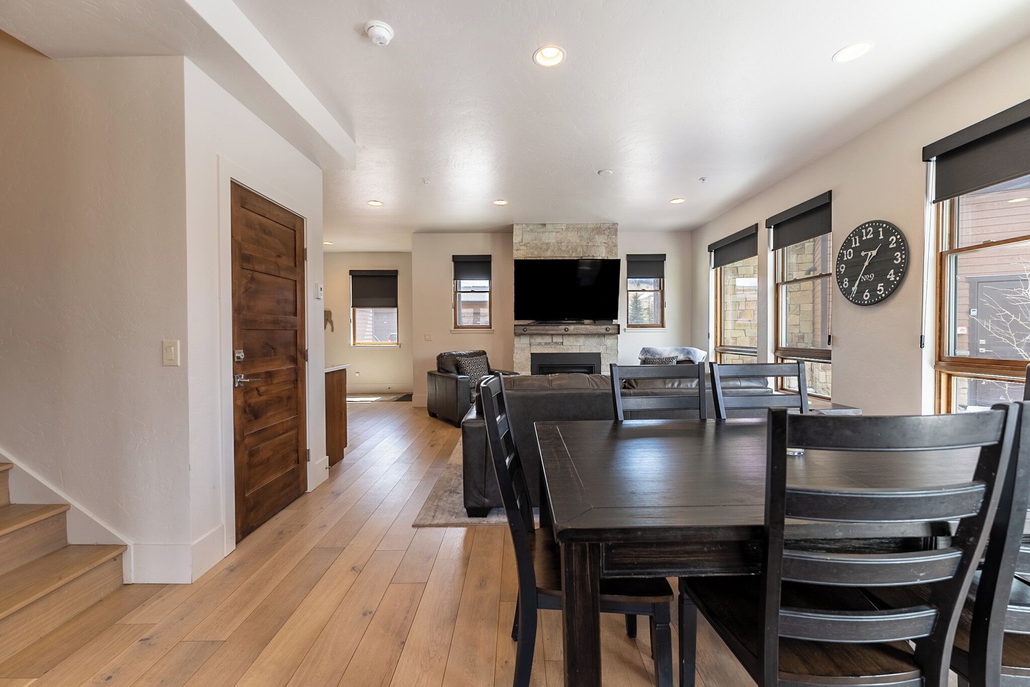A spacious living area with a dining table, chairs, a fireplace, and a large TV.