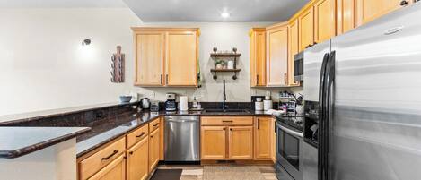 A modern kitchen with wooden cabinets, stainless steel appliances, and a granite countertop.