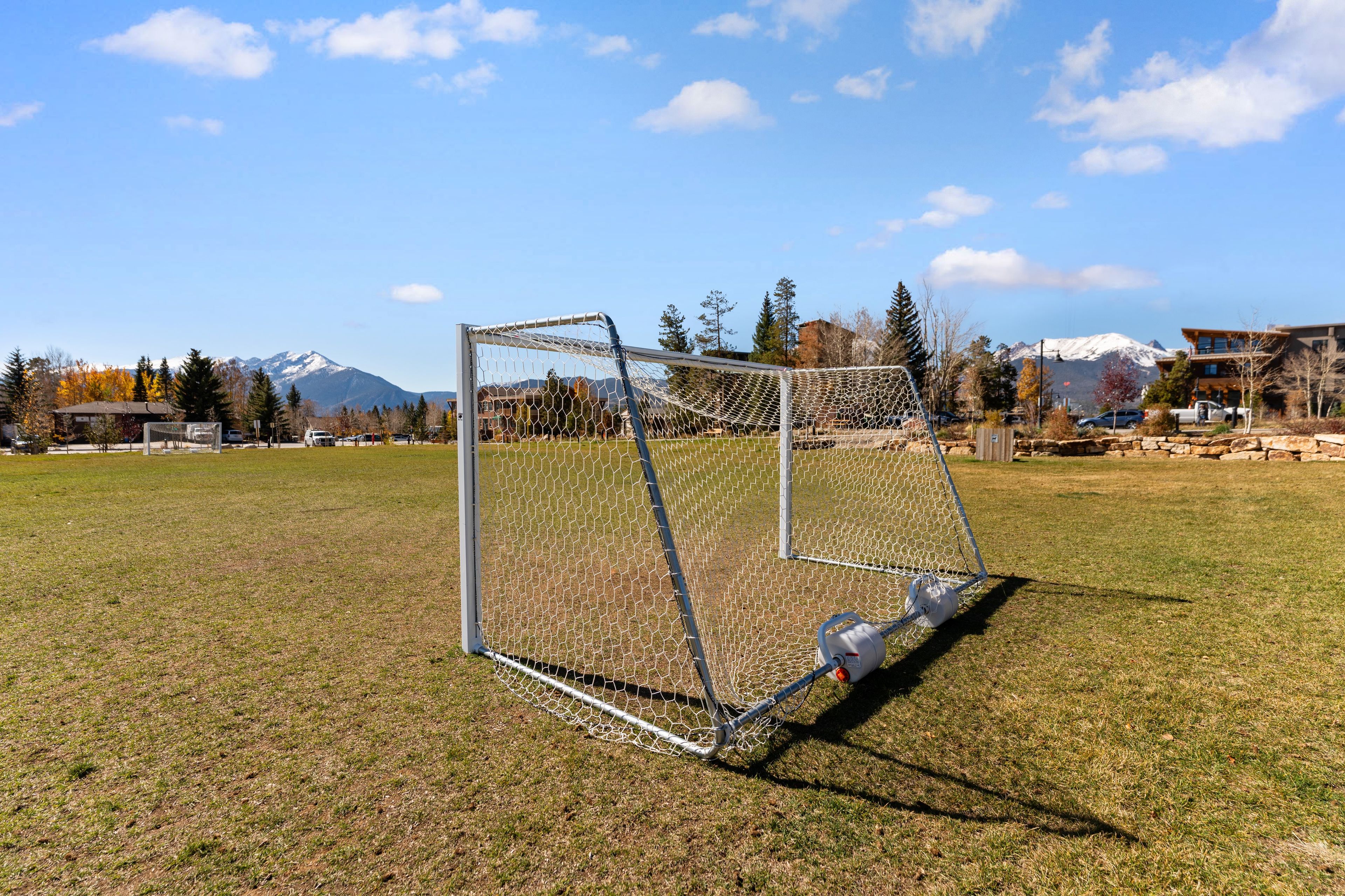 A soccer goal on a grassy field with a mountainous backdrop.