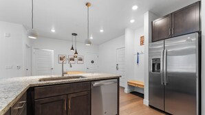A modern kitchen with dark wooden cabinets, a stainless steel refrigerator, and a granite countertop. - Clearwater Lofts #203, Building 2 (Keystone)
