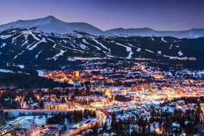 A snow-covered town with illuminated buildings and a mountain in the background. - Clearwater Lofts #203, Building 2 (Keystone)