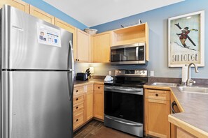 Una cocina moderna con electrodomésticos de acero inoxidable, armarios de madera y un microondas.