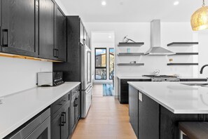 A modern kitchen with dark cabinetry, white countertops, and a central island. - Sb30s4 (Silverthorne)